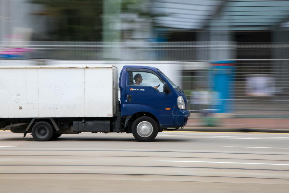 blue and white truck driving down a street