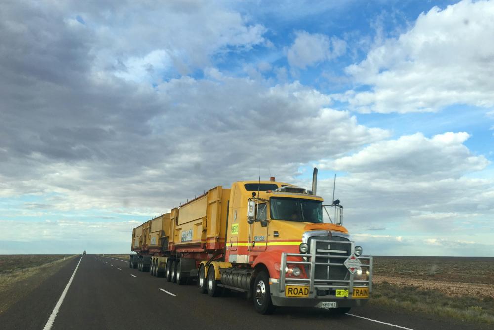 yellow semi truck driving on a highway